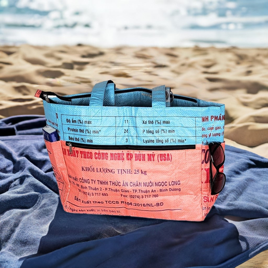 Strandtasche in blau und rot aus recycelten Reissäcken mit Reisverschluss verschließbar und Einstecktaschen außen.